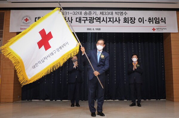 ▲10일 호텔라온제나에서 열린 대한적십자사 대구광역시지사 회장 이‧취임식에서 박명수 신임 회장이 적십자사기를 흔들고 있다(사진=대구적십자)